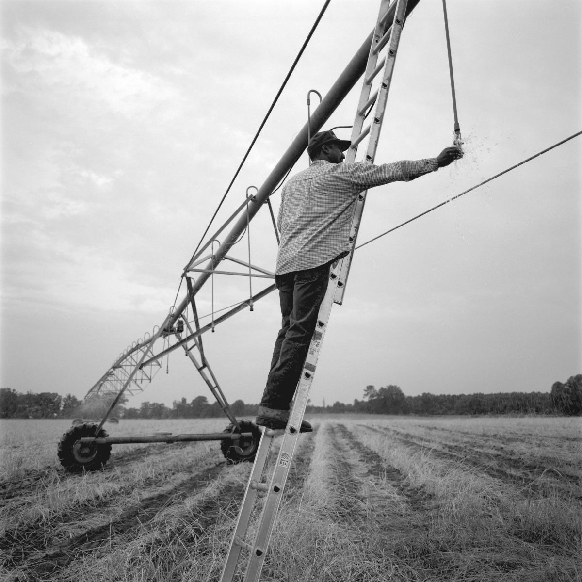 <p><center>Macon County, Georgia:</center></p>
Warren James fixes a nozzle on his newly installed irrigation system, which waters eighty acres." The irrigation system has helped, and having it is a plus with money lenders. It also allows greater flexibility choosing what crops you can plant in that field." : Images : AMERICAN BLACK FARMERS PROJECT - John Ficara